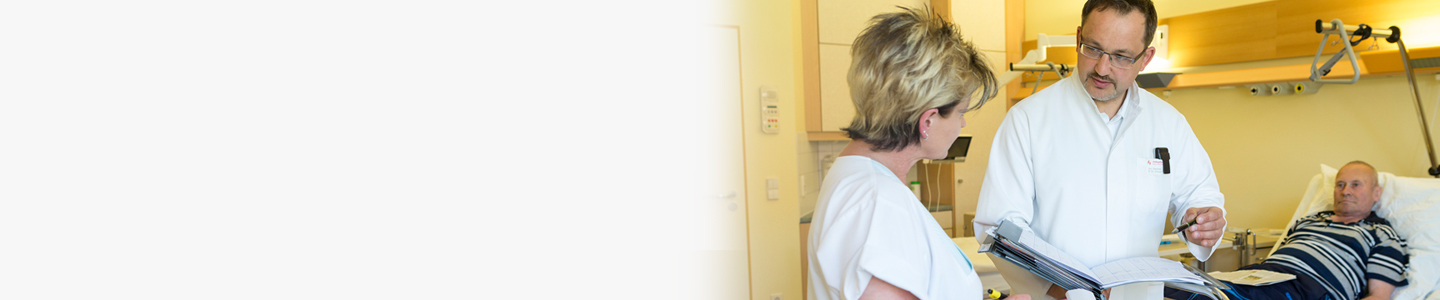 Frau im Krankenhausbett wird von freundlicher Krankenschwester behandelt